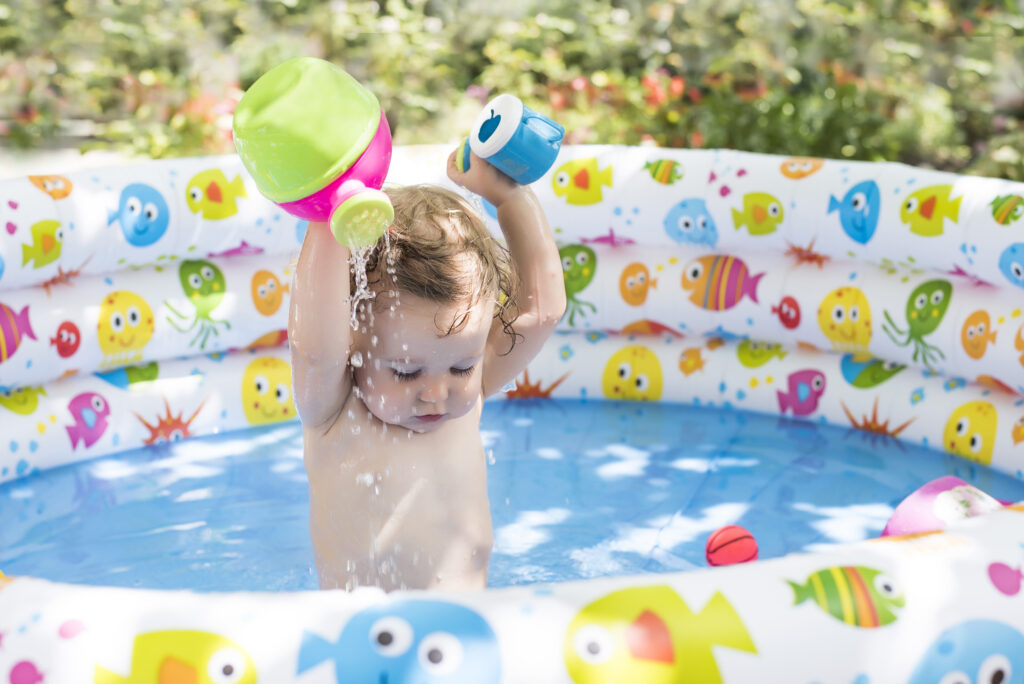 A cute little toddler playing in a colourful inflatable pool